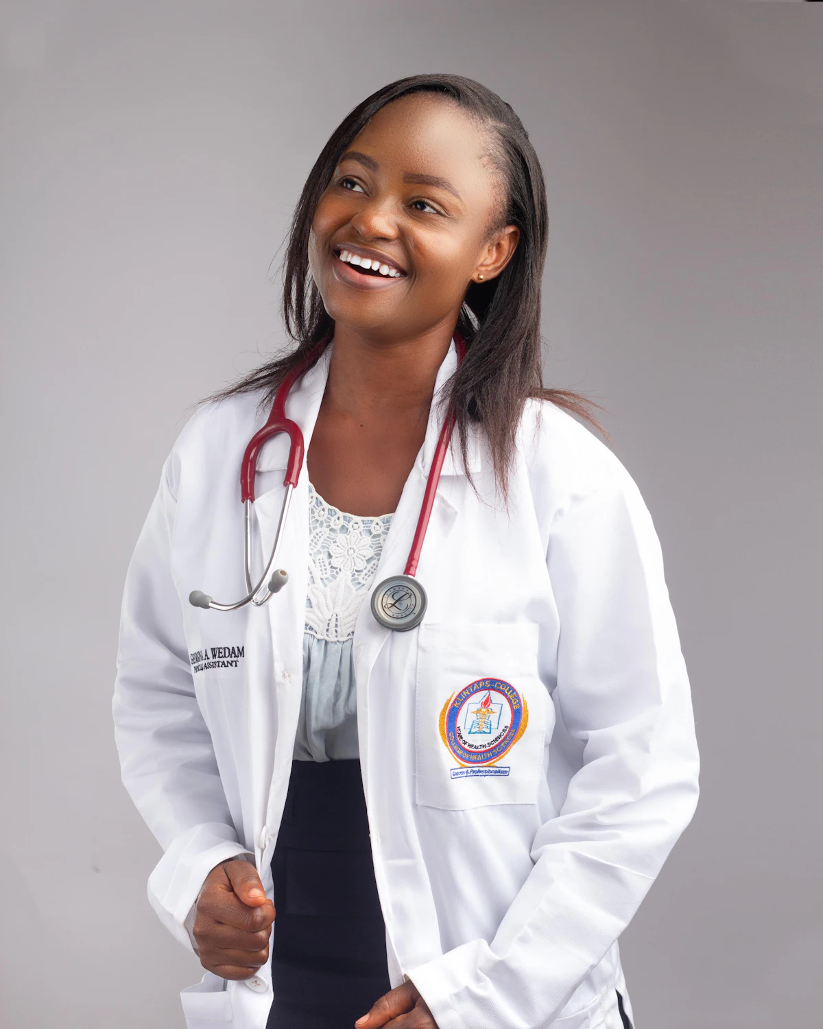Une soignante souriante en blouse blanche, un stéthoscope autour du cou.